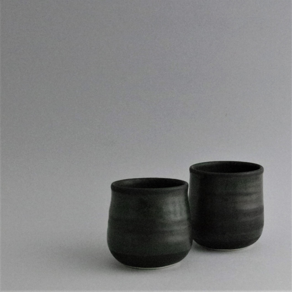 Two small beakers (e.g. for drinking) in matte black glaze with a subtle shiny overglaze