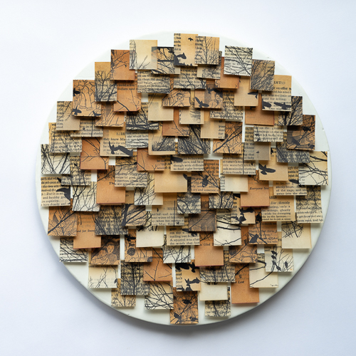 Round panel with white encaustic background and collage of old book pages in small squares attached with beeswax