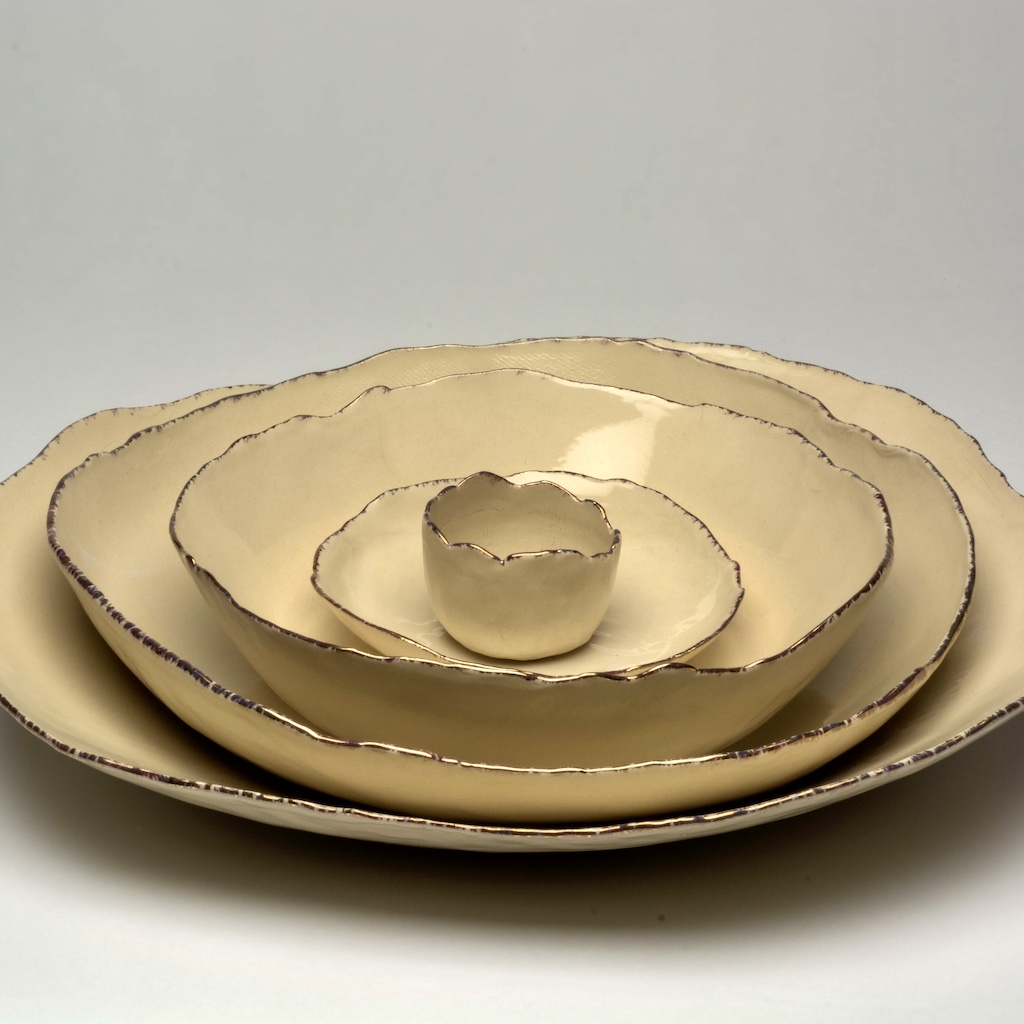Five ceramic bowls nested large to small, white, irregular rims with gold lustre