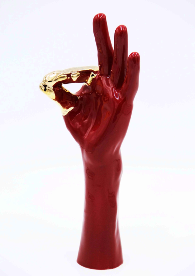 A red ceramic hand, wrist and half of a forearm featuring the “flat 9” or “flat F” handshape.